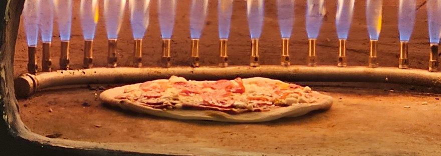 Pizza de jamón serrano cocinándose al horno de piedra