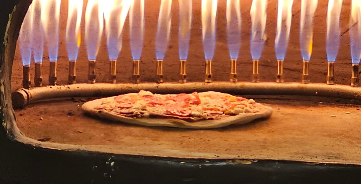 Pizza de jamón serrano cocinándose al horno de piedra